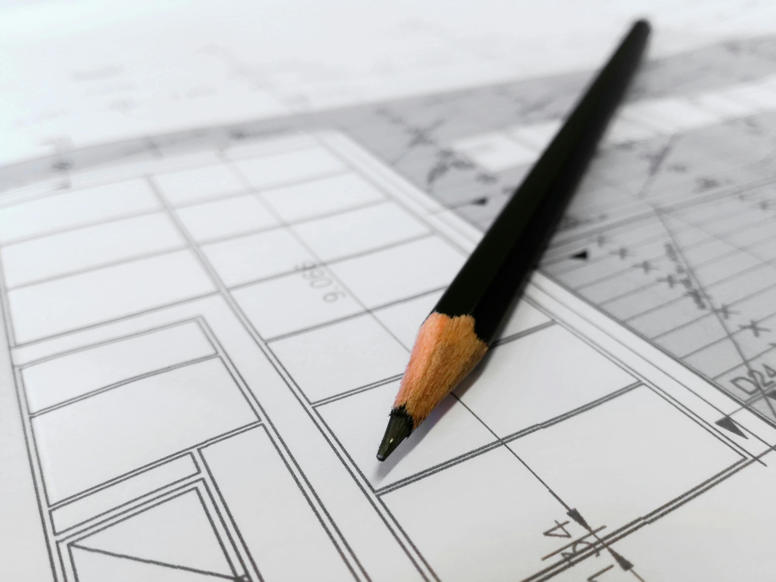 Detailed image of a black pencil resting on architectural blueprints, ideal for design and planning themes.