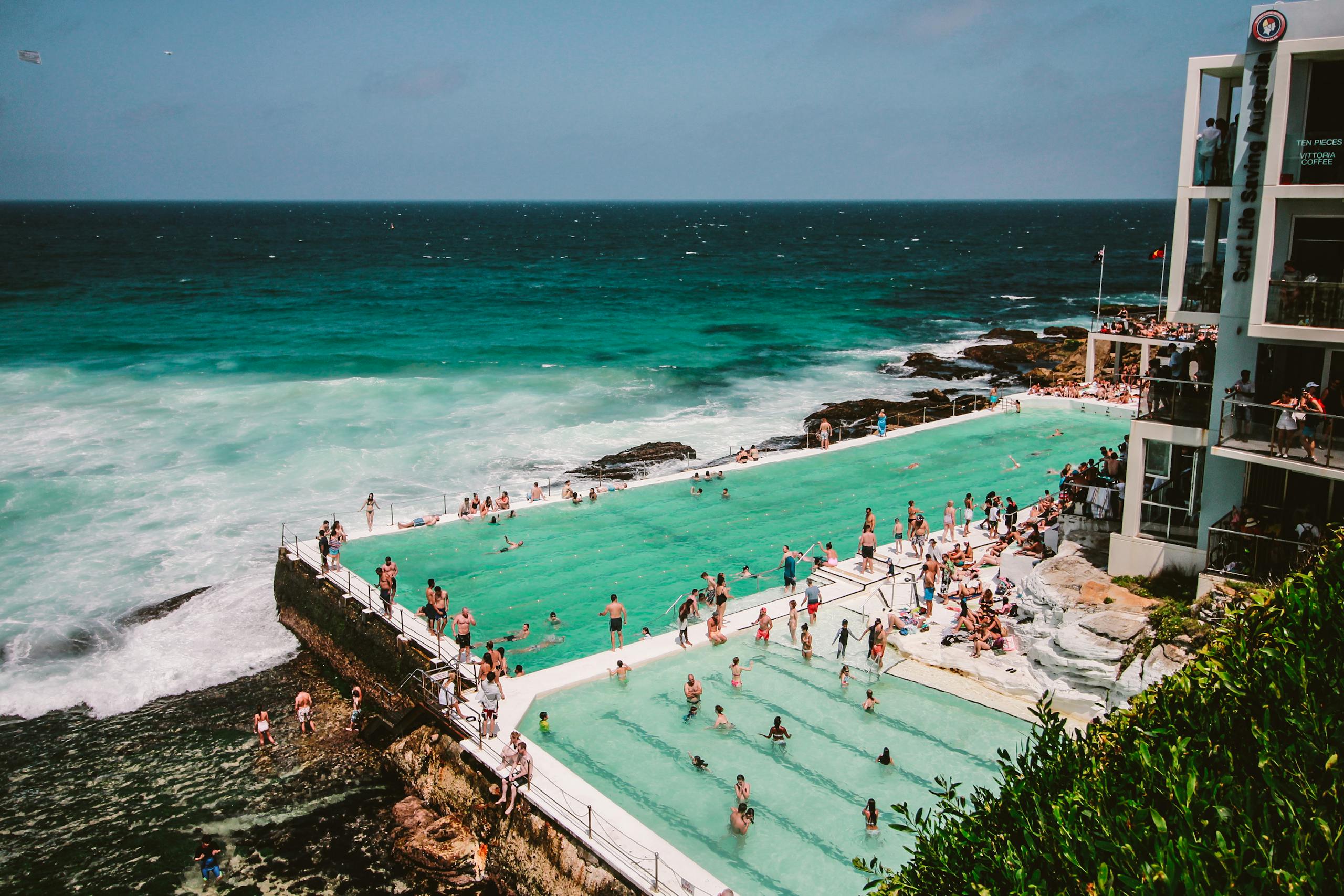 A vibrant scene of people enjoying the Bondi Icebergs swimming pool by the ocean in Sydney, Australia.