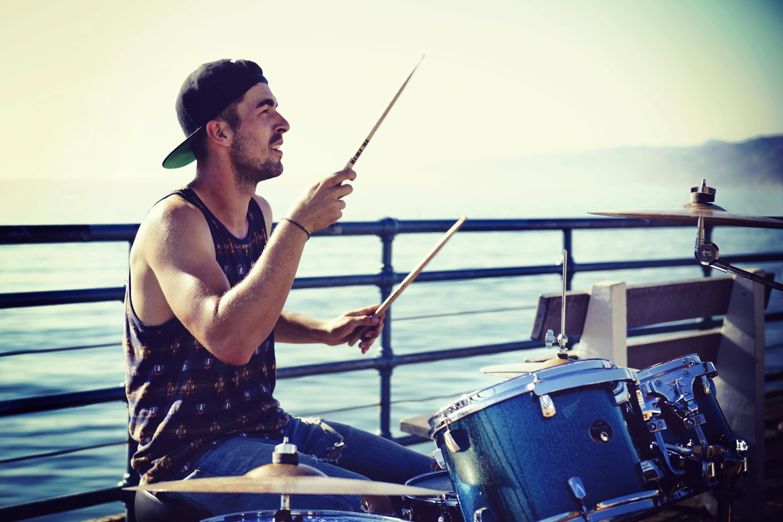 Street musician playing drums on Santa Monica Pier, capturing vibrant daytime atmosphere.